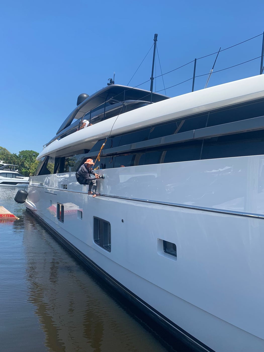 Technician machine-polishing a yacht hull